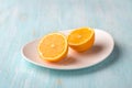 White plate with cutted on two half organic lemon on blue background